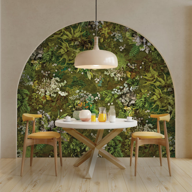 Dining area with a round table and chairs against a wall of greenery.