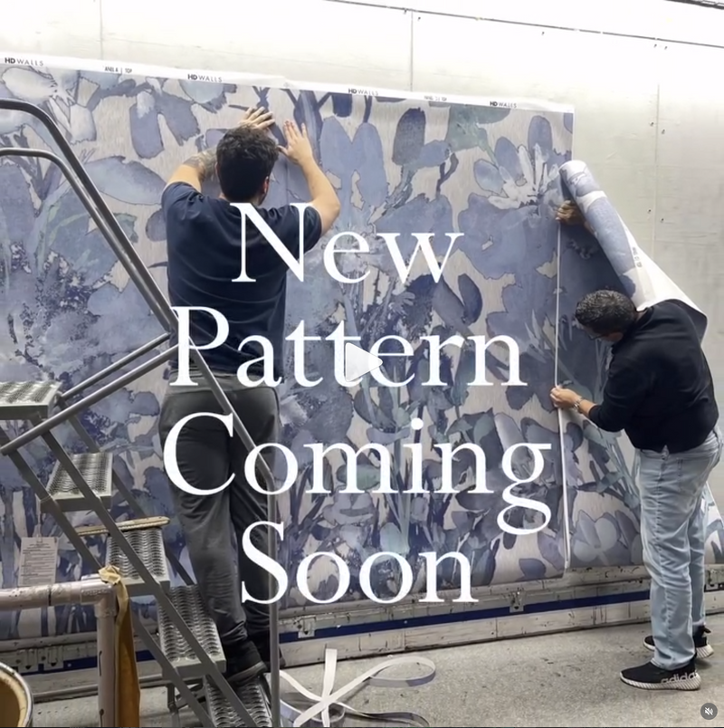 Two people working on a large floral patterned fabric with text 'New Pattern Coming Soon'.