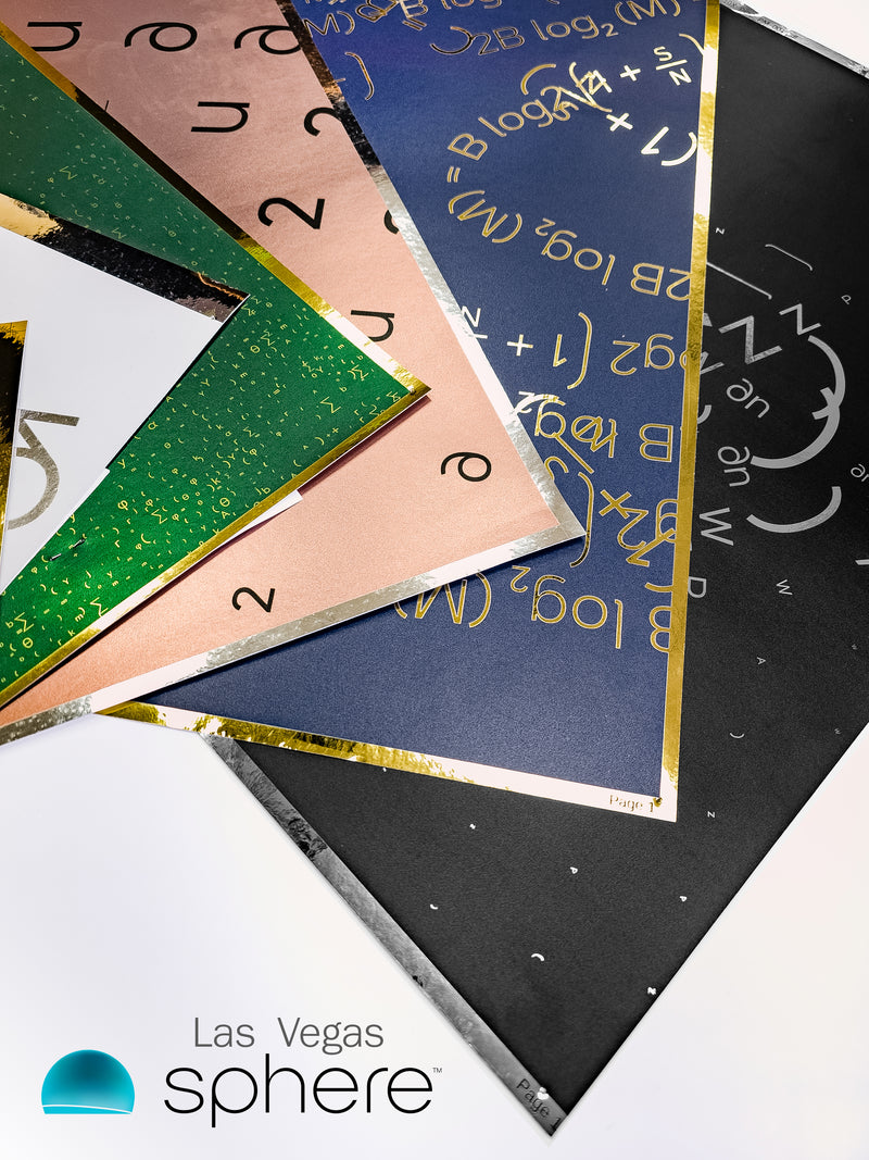 A fan of several wallpaper sample sheets for the Las Vegas Sphere, featuring mathematical equations and symbols. The sheets come in various colors including deep blue, forest green, blush pink, and charcoal black, accented with reflective gold and silver foil details.